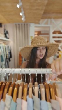 Modaya uygun bir birey, modaya uygun ve şık bir alışveriş butiği içinde çeşitli kıyafet seçeneklerini araştırıyor.