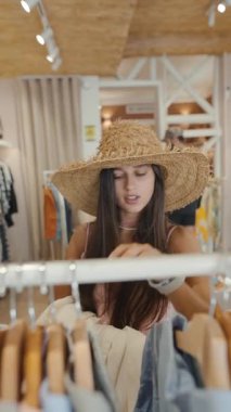 Şık ve şık bir kadın modaya uygun bir butik ortamında elbise raflarında gezinmekten zevk alır.