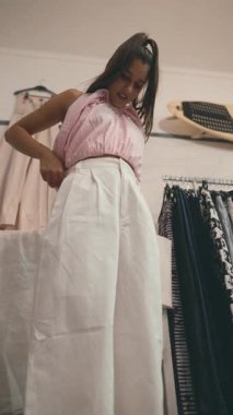 Moda mankeni şık ve şık bir butikte yüksek bel beyaz pantolon deniyor.