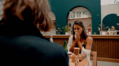Canlı bir kafede iki kişi arasındaki samimi bir an onların ham duygularını etkili bir şekilde yakalıyor.