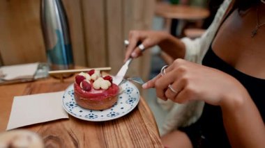 Bir kadın sıcak ve davetkar bir atmosferde taze meyvelerle süslenmiş canlı bir tatlıdan zevk alır.