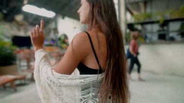 Genç bir kadın hareketli ve hareketli bir pazarı zevkle keşfediyor, modaya uygun kıyafetler ve şık aksesuarlar sergiliyor.