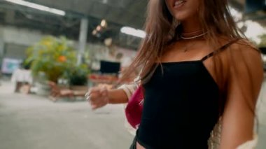 Modayı takip eden genç bir kadın hayat dolu, hareketli bir şehir ortamında rahatça yürüyor.