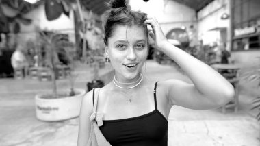 Çarpıcı ve büyüleyici bir siyah beyaz görüntü canlı bir şehir ortamında neşe saçan genç bir kadını yakalıyor.