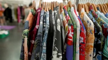 Yeni moda bir butikte sergilenen renkli çiçekli gömleklerin geniş yelpazesini keşfedin.