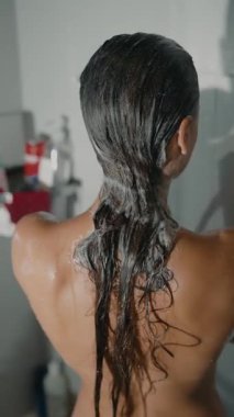 Huzurlu ve rahatlatıcı bir sahne. Duşta şampuanı nazikçe süren bir kadın. Güzelce gösterilen saç bakım rutinleri.