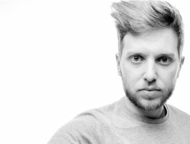 Beyaz bir arka planda şık, yaratıcı bir saç stili olan güzel bir genç adam.