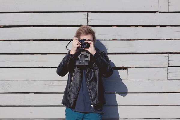 a fashionable man with a film camera in a black leather jacket