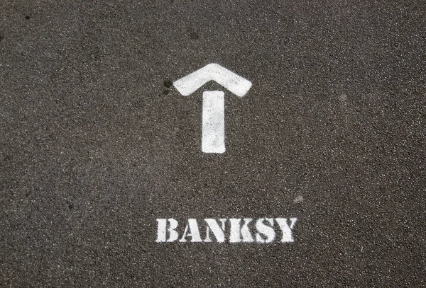 İngiltere, Weston-super-Mare 'de bir kaldırıma sprey boyayla boyanmış bir tabela, ziyaretçileri Banksys sanat sergisi Dismaland' a yönlendiriyor..