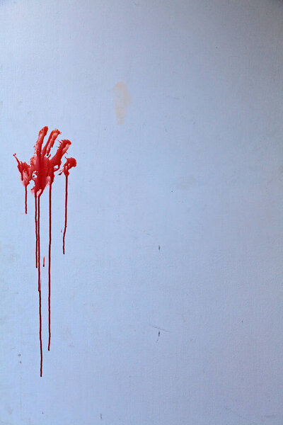 A red handprint, possibly blood, or possibly paint, on a grimy wall