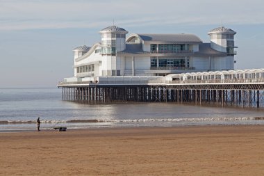 Weston-super-Mare 'deki Grand Pier, İngiltere' de güneşli bir kış gününde ön planda bir balıkçıyla.