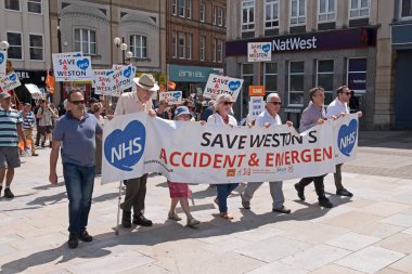 Göstericiler, Weston General Hospital 'daki A & E bölümünün bir gecede kapatılmasını ve 6 Temmuz 2019' da İngiltere 'nin Weston-super-Mare kentindeki North Somerset kentindeki sağlık hizmetlerine yapılacak olası kesintileri protesto ettiler.