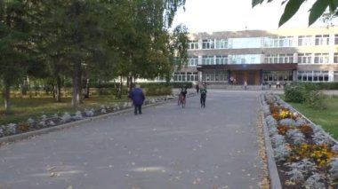 Çocuklar okuldan sonra okul bahçesinde bisiklet sürerler..