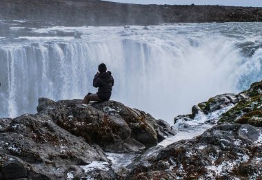 Selfoss 'a bakan bir turist vadinin kenarına atlıyor.