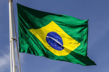 Arka planda mavi bir gökyüzü dalgalanırken rüzgarda dalgalanan Brezilya bayrağına yaklaş.