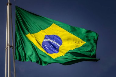 Arka planda mavi bir gökyüzü dalgalanırken rüzgarda dalgalanan Brezilya bayrağına yaklaş.