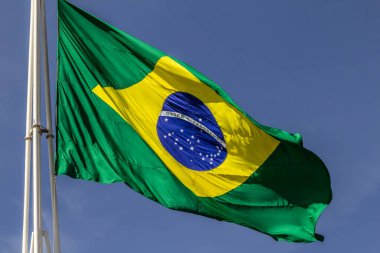 Arka planda mavi bir gökyüzü dalgalanırken rüzgarda dalgalanan Brezilya bayrağına yaklaş.