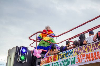 A drag queen in a colorful dress, dancing on top of a float, enjoying the LGBTQIA Pride Parade in Goiania.