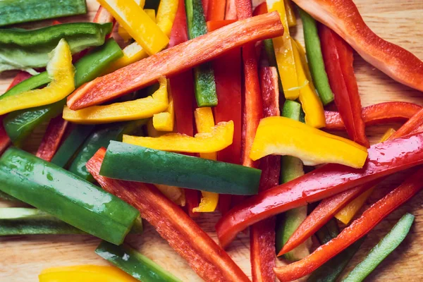 Kırmızı biber, yeşil biber ve ahşap masada sarı biber.