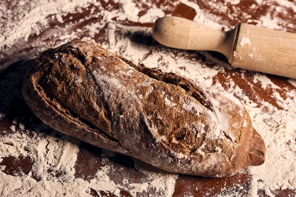 Ahşap masanın üzerinde un bulunan el yapımı ekmek.