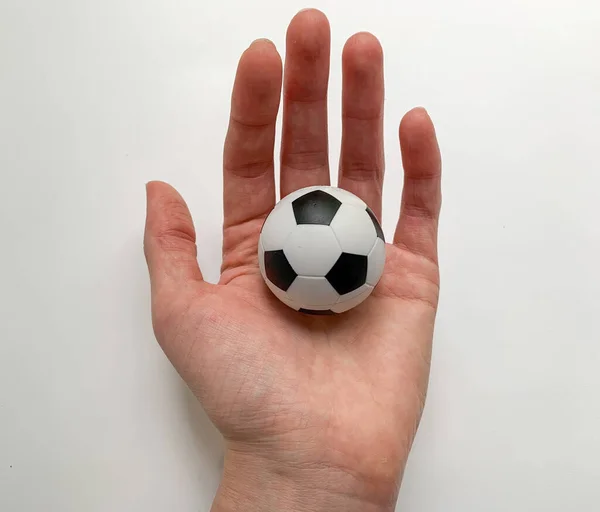 A small soccer ball in the hand of a girl on a white background.