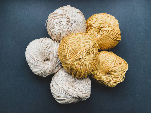 Mustard and beige yarn for knitting on a black background. Needlework, crocheting, Hobbies.