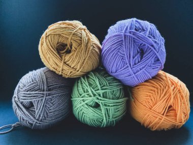 Siyah arka planda örgü örmek için renkli iplik. Mor, yeşil, gri ve turuncu renkli iplikler. Örgü, örgü, dikiş. Ürün yaratma kavramı.