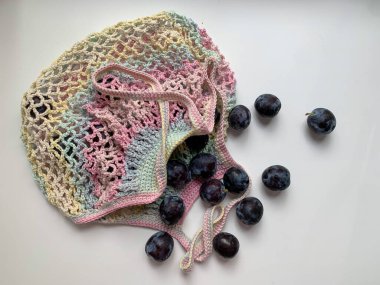 Beyaz arka planda, çok renkli bir torba içinde taze erik. Yukarıdan bir fotoğraf. Sıfır kayıp. Ekoloji. Çevreye dikkat et. Düzgün beslenme, vejetaryenlik