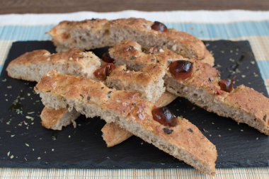 Çeri domatesli ev yapımı ekmek Focaccia 'sı ve tahta tabanlı zeytin yağı.