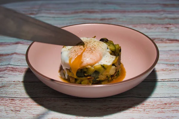 Düşük sıcaklıkta pişirilmiş sebze ve yumurta turtası. Bıçak yumurta sarısını kırıyor.