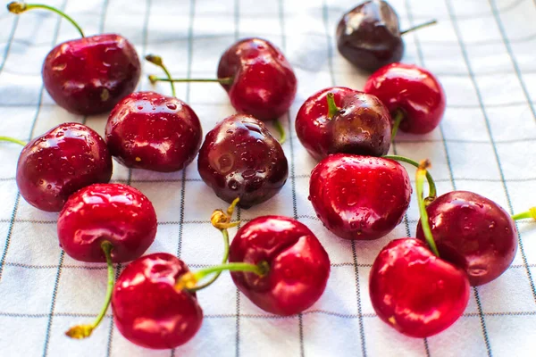 Beyaz arka planda su damlacıkları olan taze kirazlar.