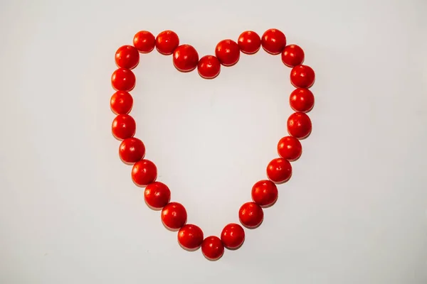 Top view of heart with cherry tomatoes on a white background. Heart made with cherry tomatoes