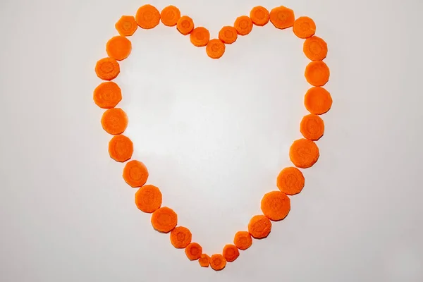 Top view of heart with carrot slices on a white background