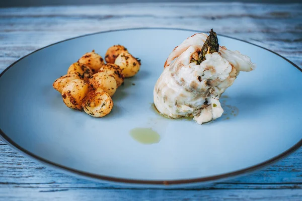İçinde kuşkonmaz ve açık mavi tabakta patates topları olan sarılmış balıkları kapat.
