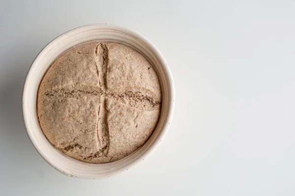 Banneton 'ın içinde çiğ ekmek hamuru topu ve taze kesilmiş haç. Boşluğu kopyala