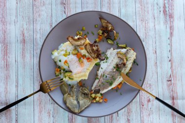 Sebzeli ızgara balık, yumurta ve enginar. Üst görünüm