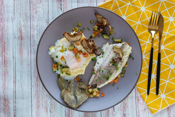 Sebzeli ızgara balık, yumurta ve enginar. Üst manzara ve sarı peçete