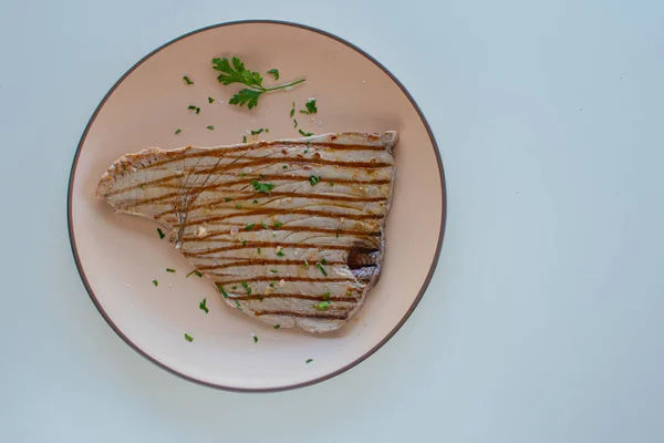 Yuvarlak tabakta ızgara ton balığı bifteği. Kopyalama alanı ve beyaz arkaplan