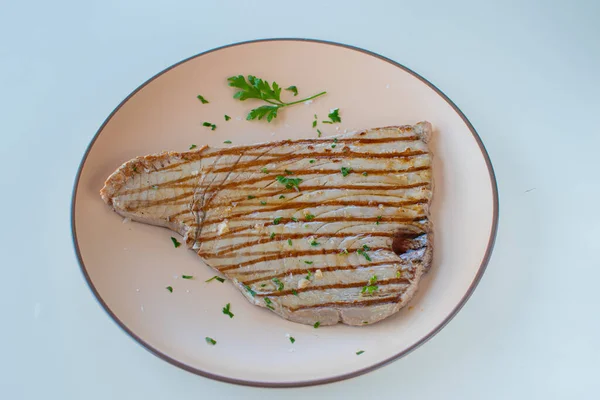 Yuvarlak tabakta ızgara ton balığı biftek.