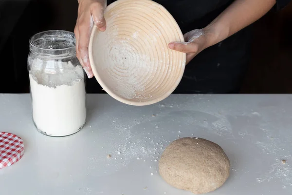 Kadının elleri banneton 'a un atıyor.