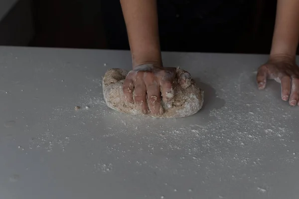 Kadının elleri siyah arka planda un yoğuruyor.