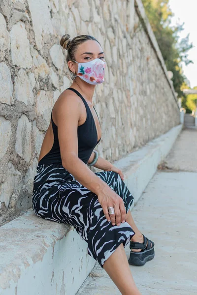 Siyah elbiseli genç sarışın kadın, küstah bakışlarıyla ufka bakıyor.