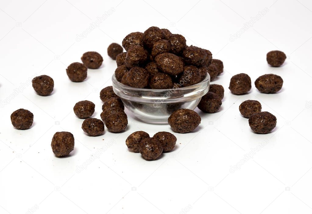 Choco pops or Chocolate balls grouped in a transparent bowl for morning healthy calorie breakfast and few placed on a surface