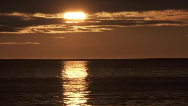 Золотое заходящее солнце, отражающееся на океанской воде — стоковое видео