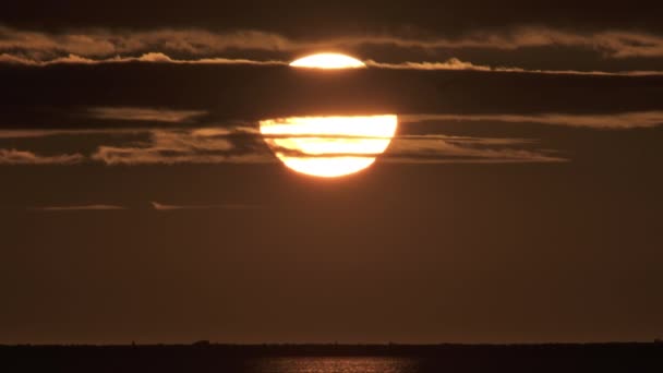 Jättesol som sänker sig genom molnen över havsvägen — Stockvideo