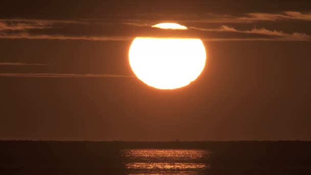 Giant sun setting over ocean and people walking — Stock Video