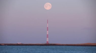 Okyanus kıyısındaki verici kulesinin üzerinde dolunay belirliyor. İzlanda kapanıyor.