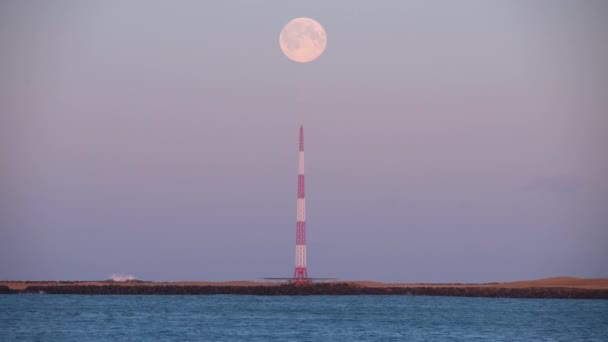 Luna llena sobre la torre del transmisor junto al mar Islandia de cerca — Vídeos de Stock