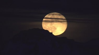 Dağların ve ince bulutların ardında yükselen Süper Ay İzlanda