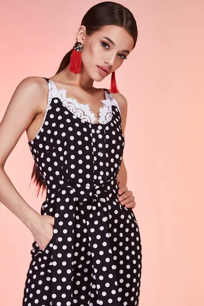 Beautiful sexy woman pretty face long brunette hair wear black polka dot skinny dress fashion style clothes for business woman office casual walk summer collection jewelry earrings glamour model pose.